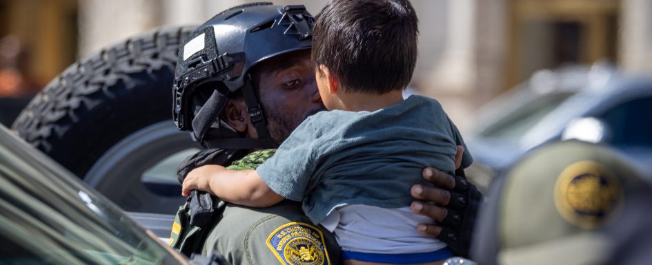 An Ice agent holding a toddler